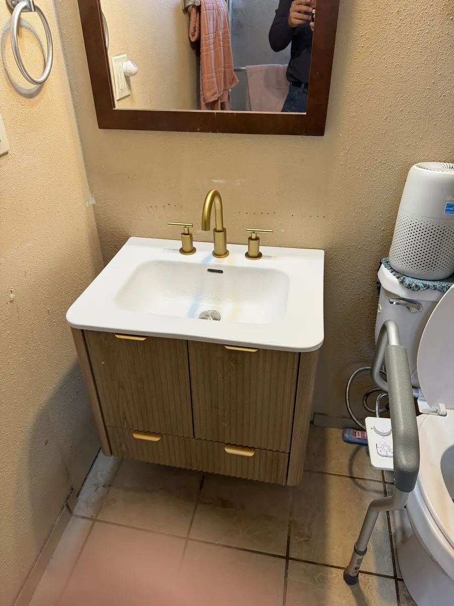 Floating vanity and brass faucet installed in a bathroom