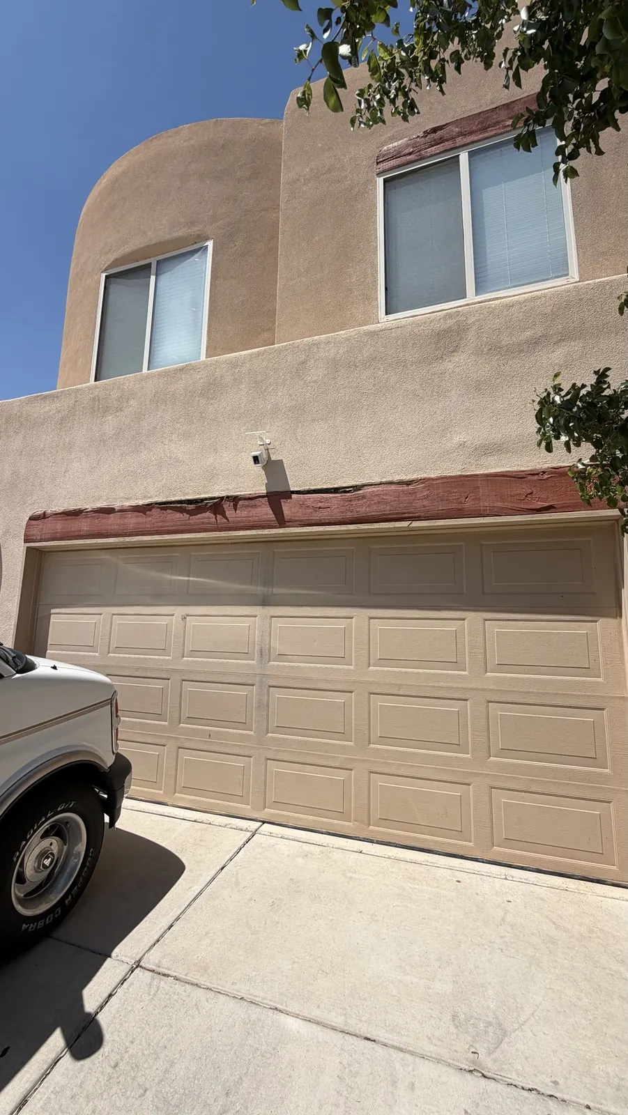Two-story stucco house with rotted garage and window headers