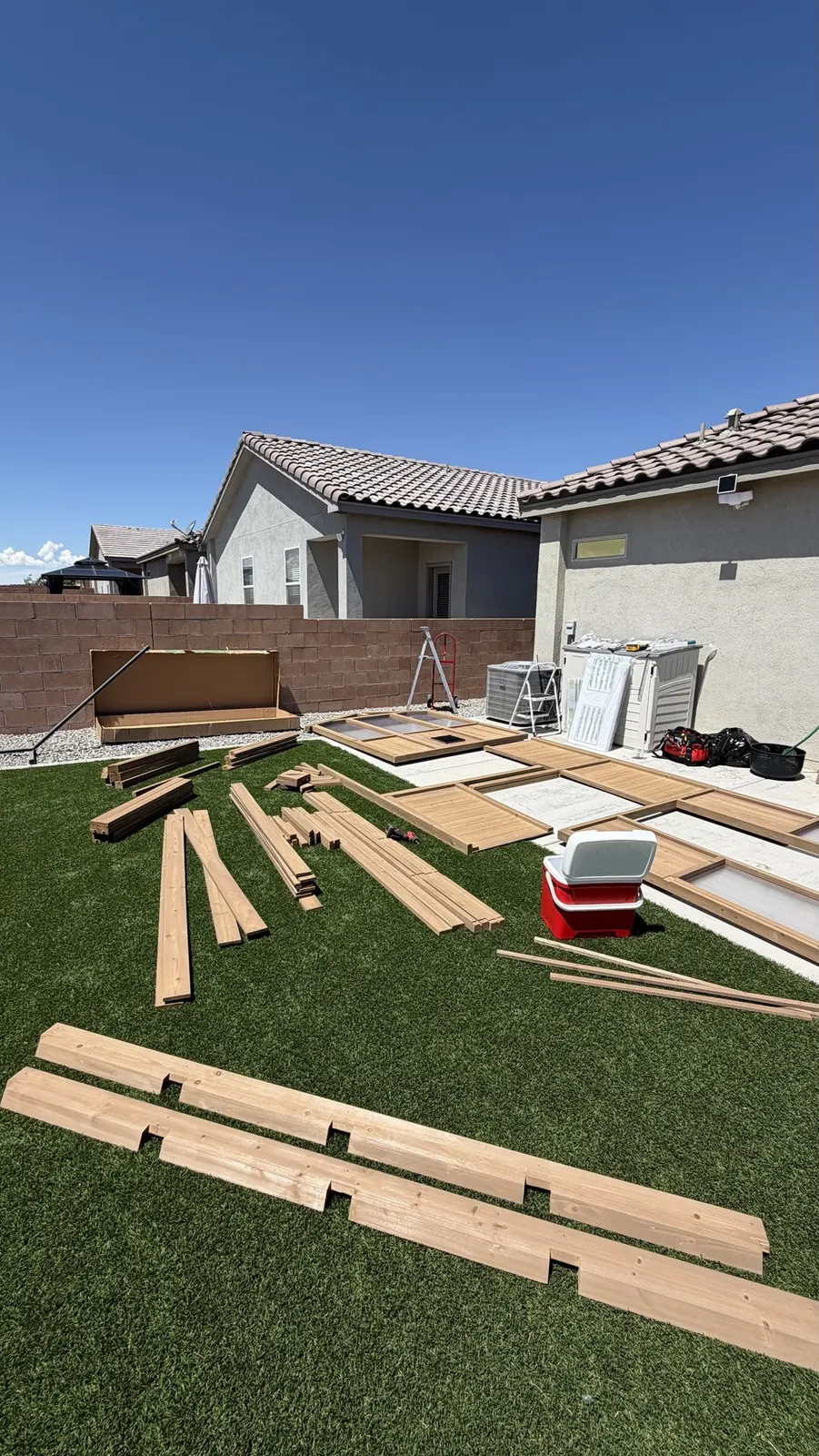 Greenhouse kit parts laid out on the lawn before assembly