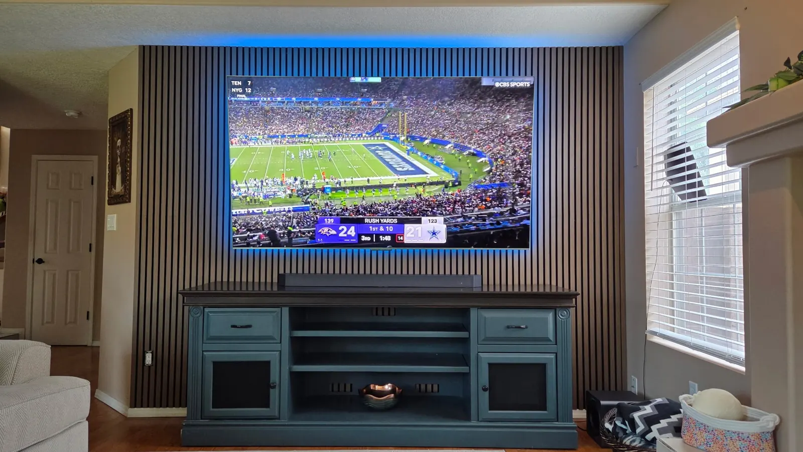 Mounted TV on a slat wall with LED backlight, game on screen