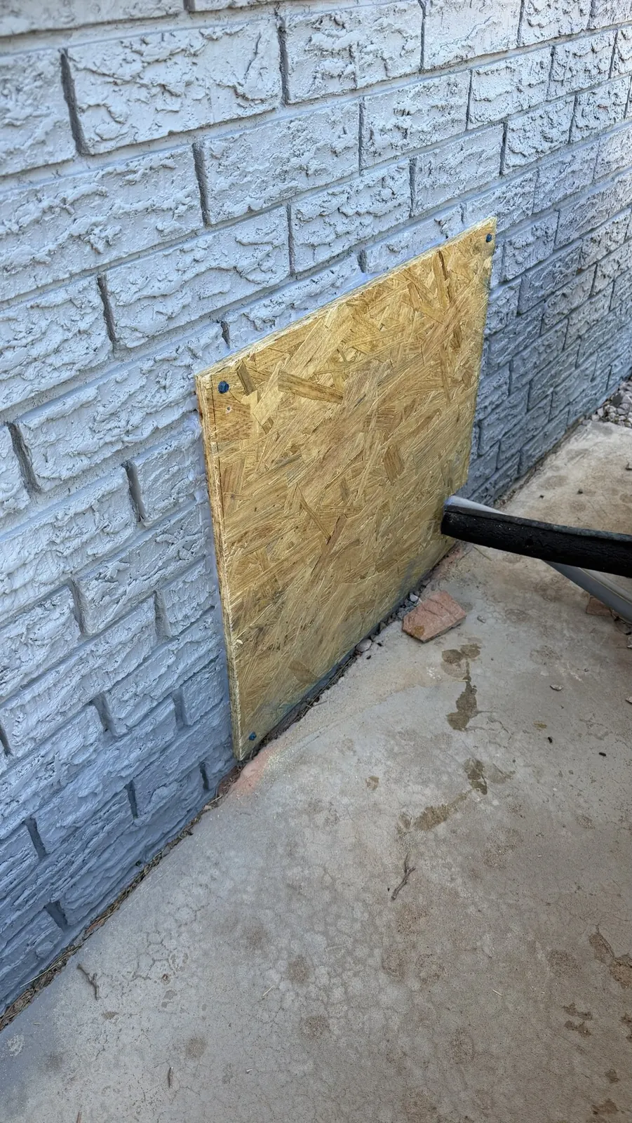 Opening in a painted brick wall boarded and sealed